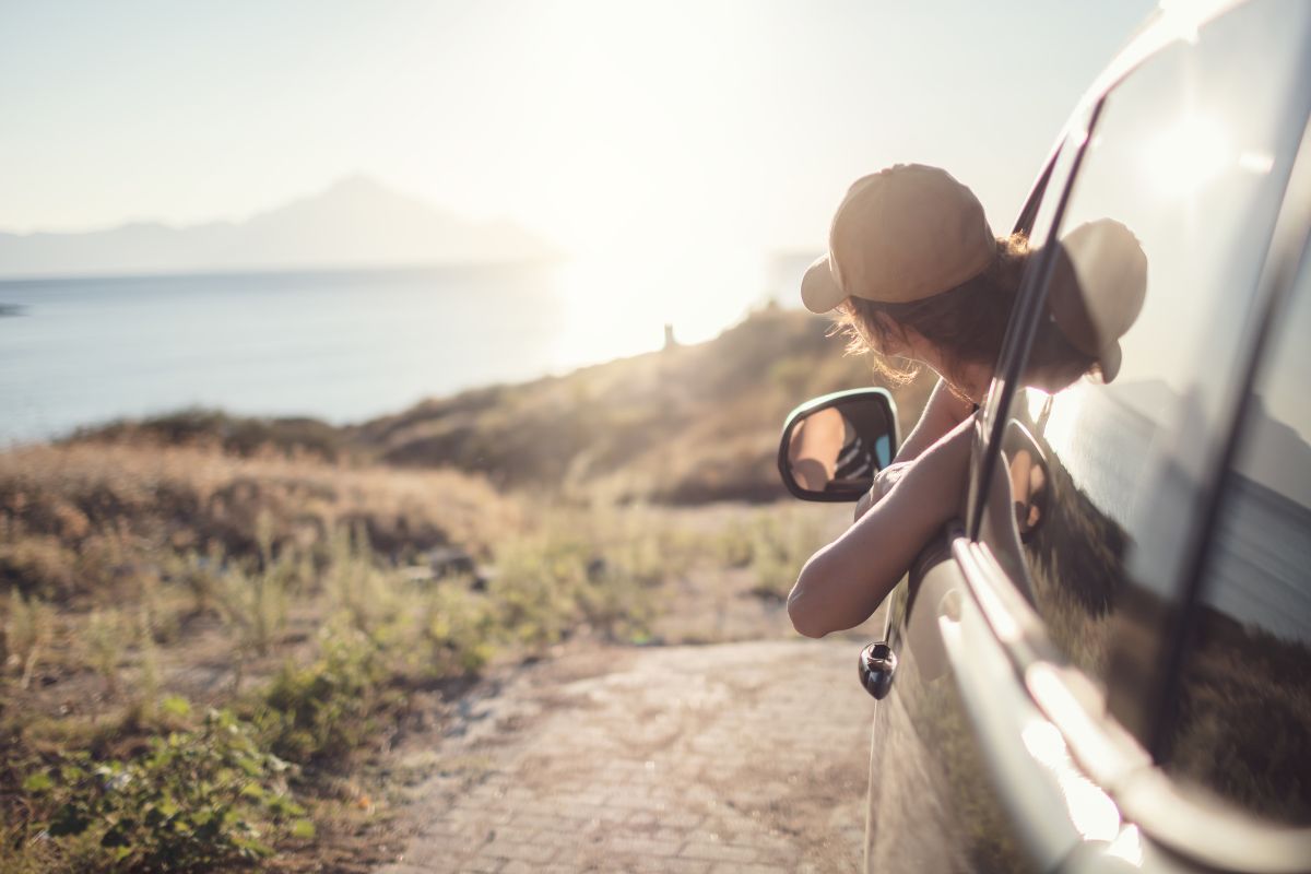 A picture of someone resting on her car. 