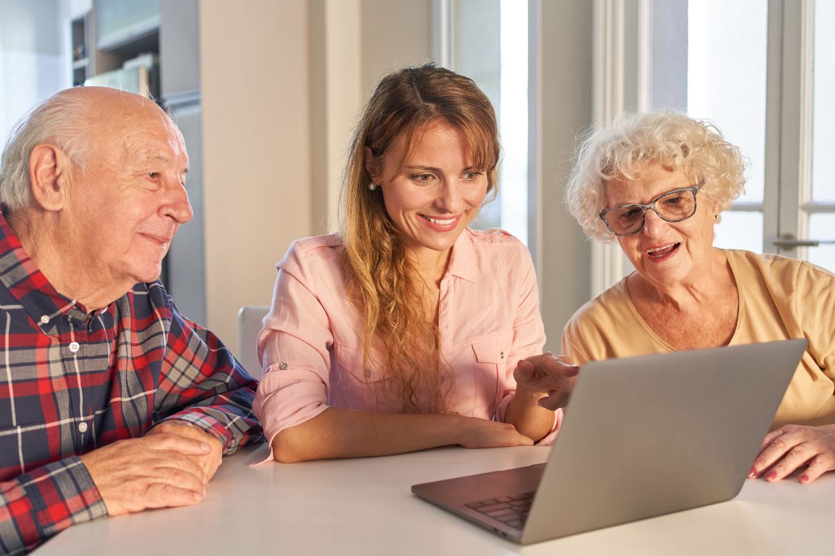 A picture of someone helping elderly use a gadget.