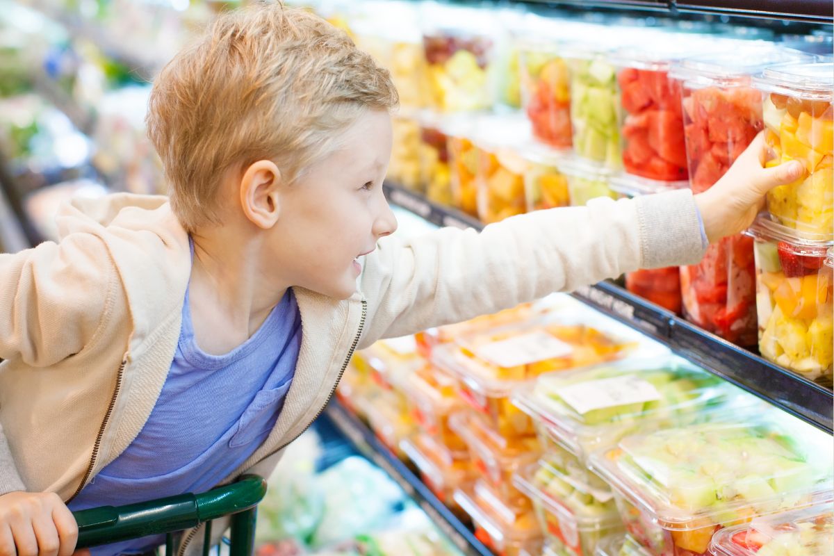A picture of child picking a packaged fruit. 