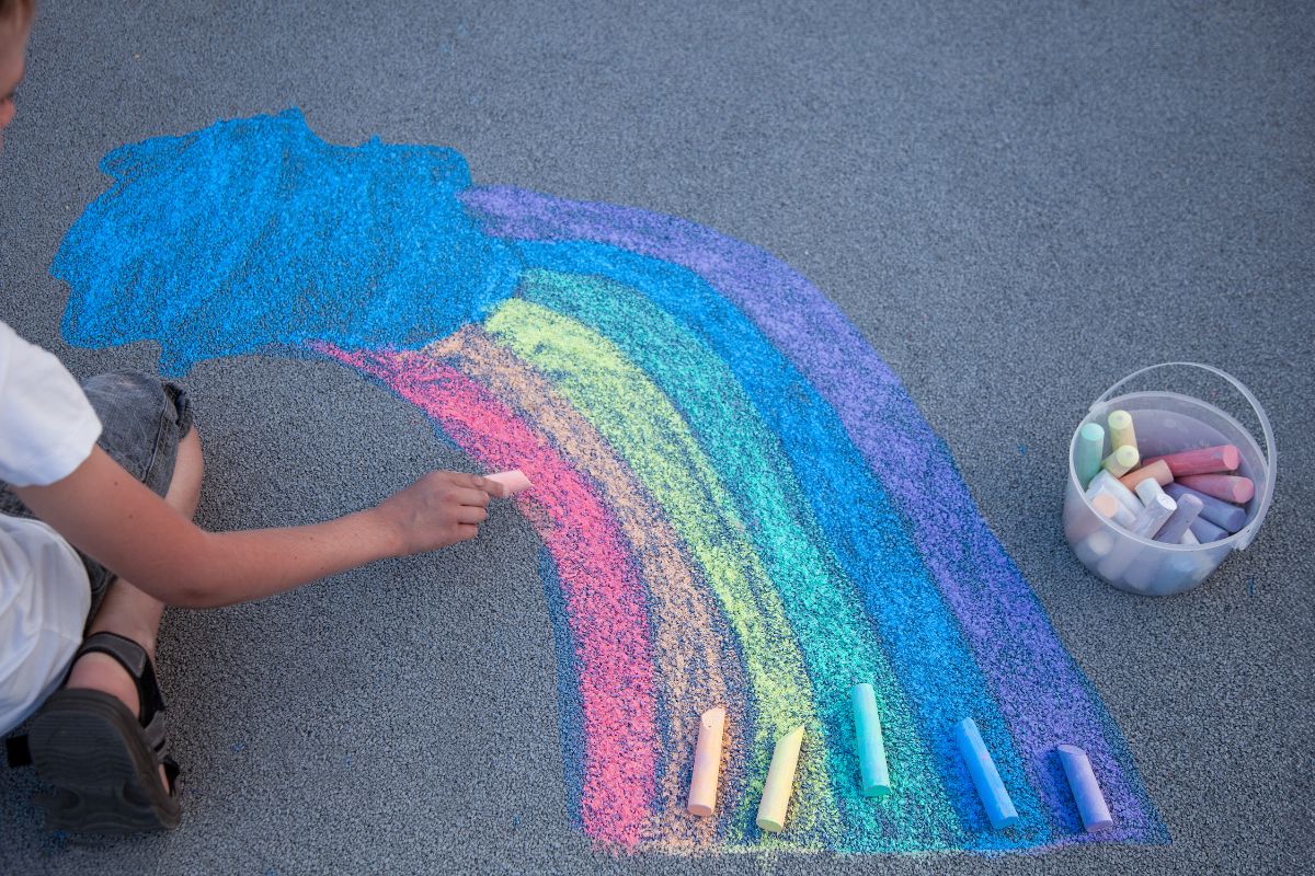 Picture of a child using chalk to make sidewalk art.