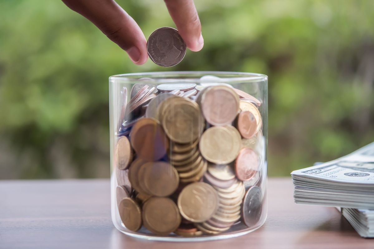 A picture of someone putting money in a jar. 