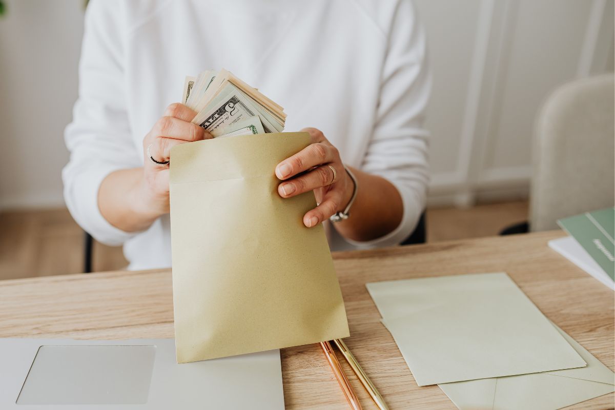 A picture of someone putting money in an envelope. 