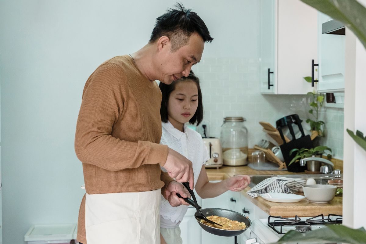 A picture of a father cooking for his daughter.