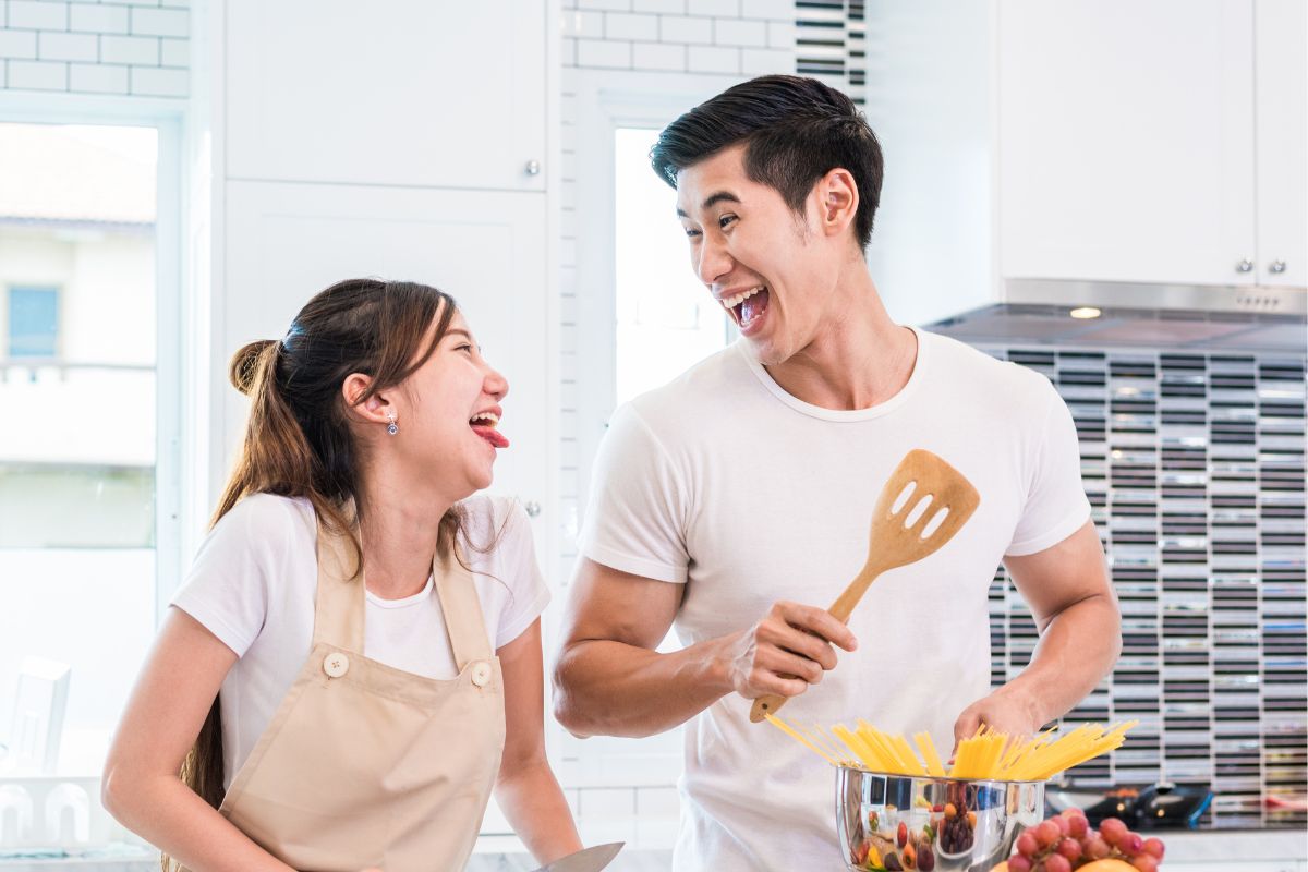 A picture of a couple smiling while cooking. 