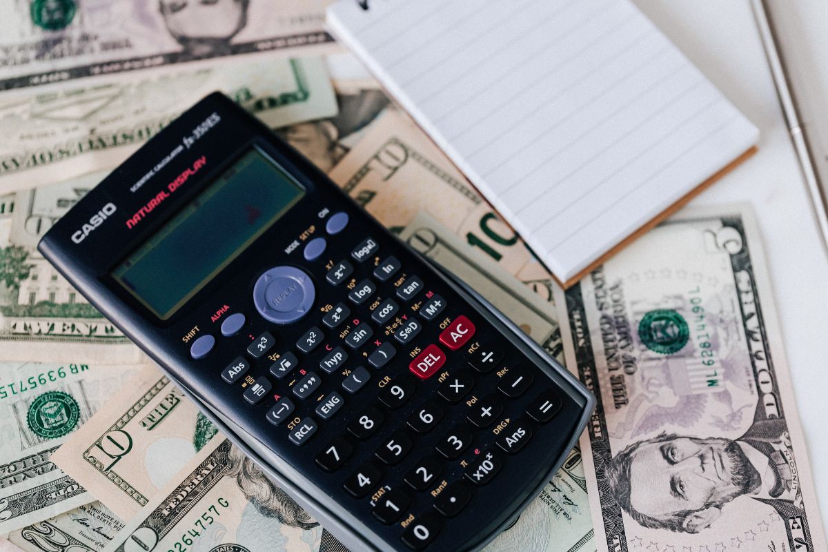 A picture of a calculator and a pile of money. 