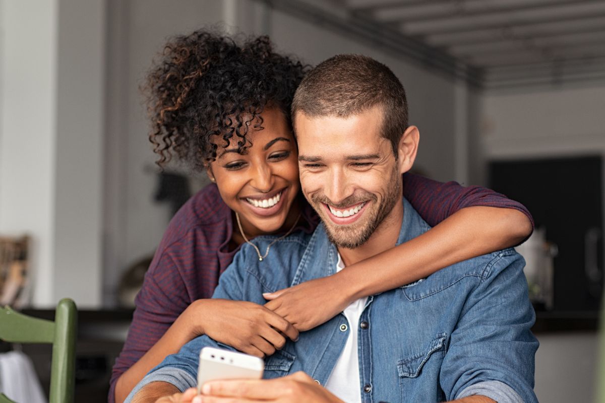 A picture of a couple looking at a phone.