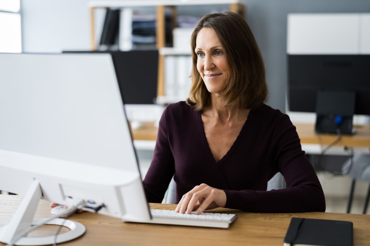 A picture of someone smiling while looking at their computer.