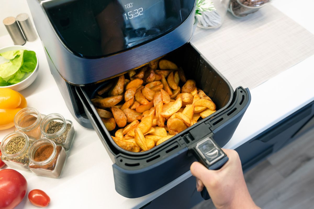 A picture of someone using an air fryer.