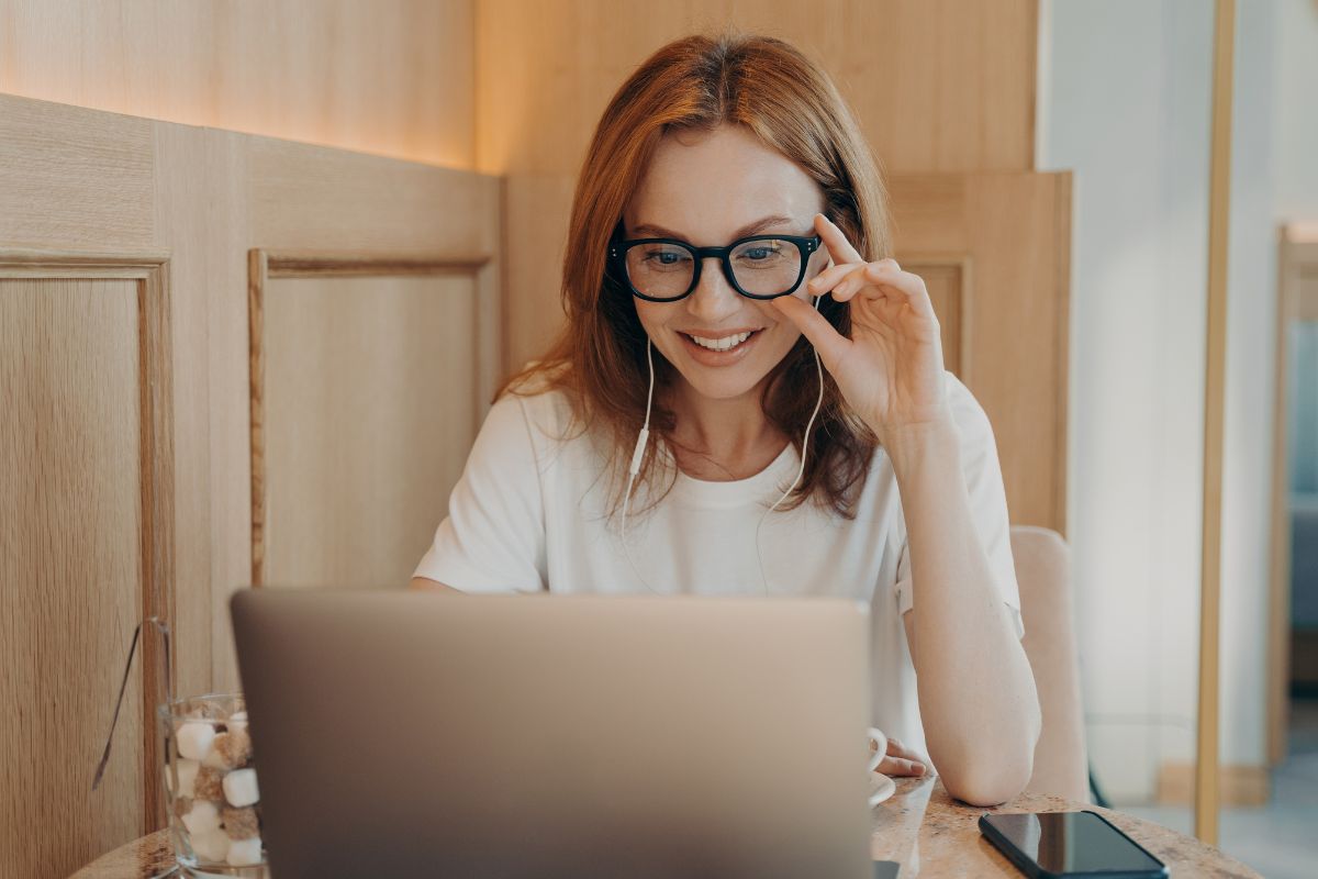 A picture of someone smiling while using their laptop.