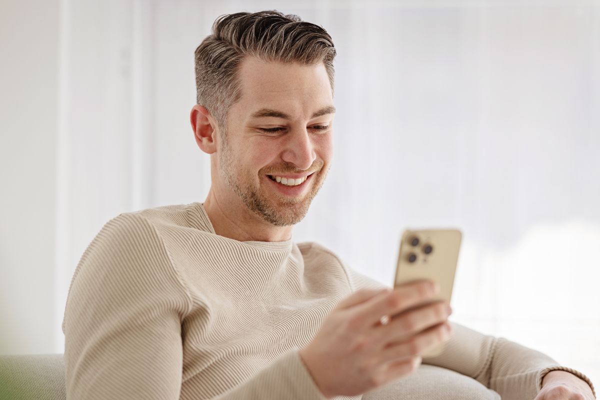 A picture of someone smiling while using their phone. 