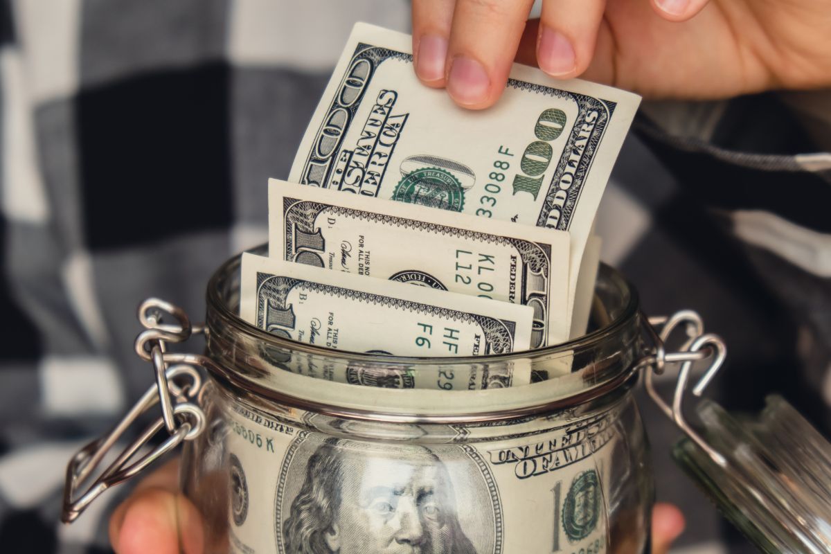 A picture of someone handling money from a jar. 