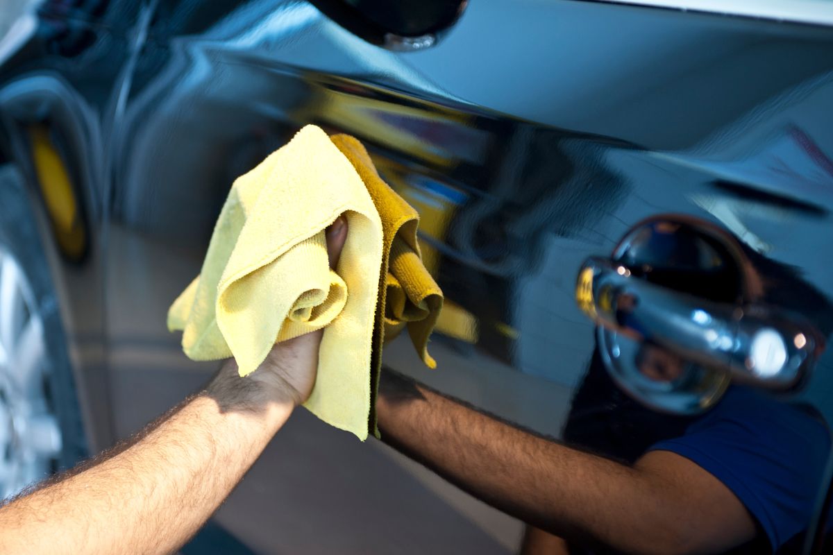 A picture of someone wiping a car. 
