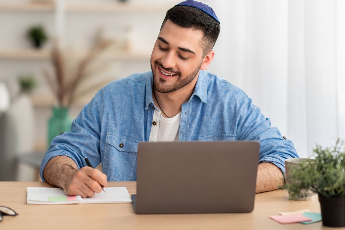 A picture of someone smiling while in their laptop. 