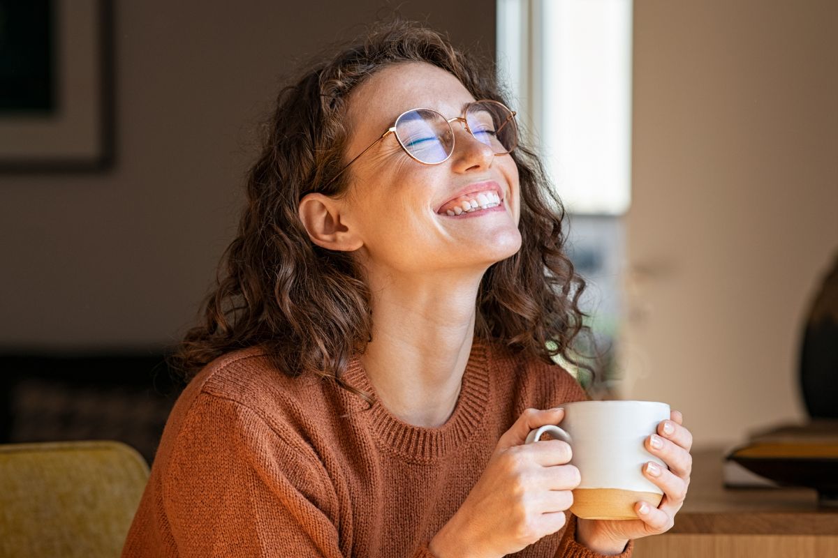 A picture of someone smiling while drinking coffee.