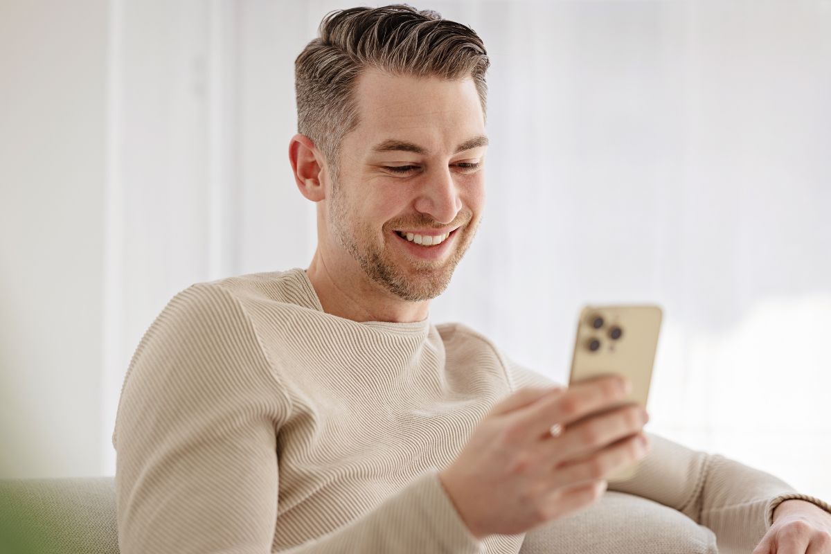 A picture of someone smiling while on the phone. 