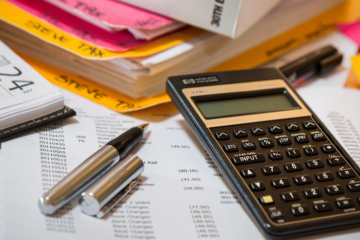 A picture of a calculator with notes. in the background. 