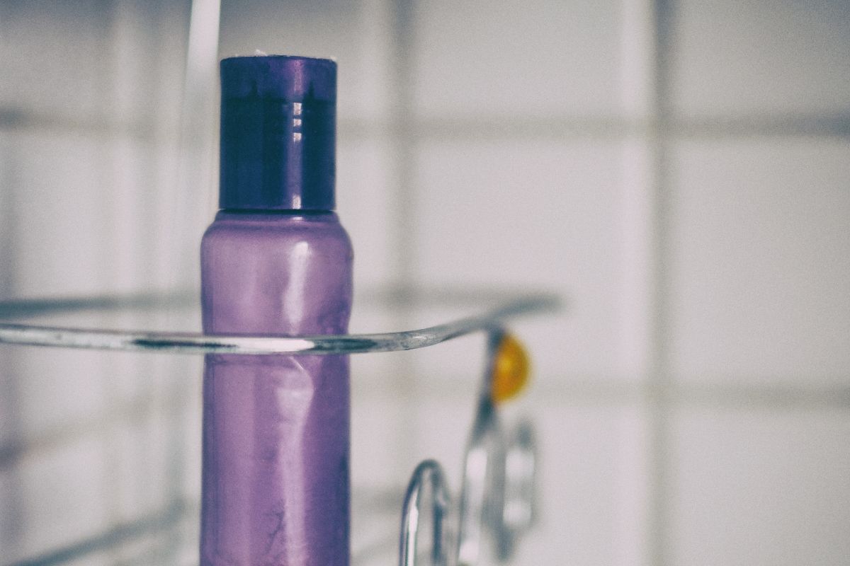 A picture of a shower caddy with a purple bottle. 