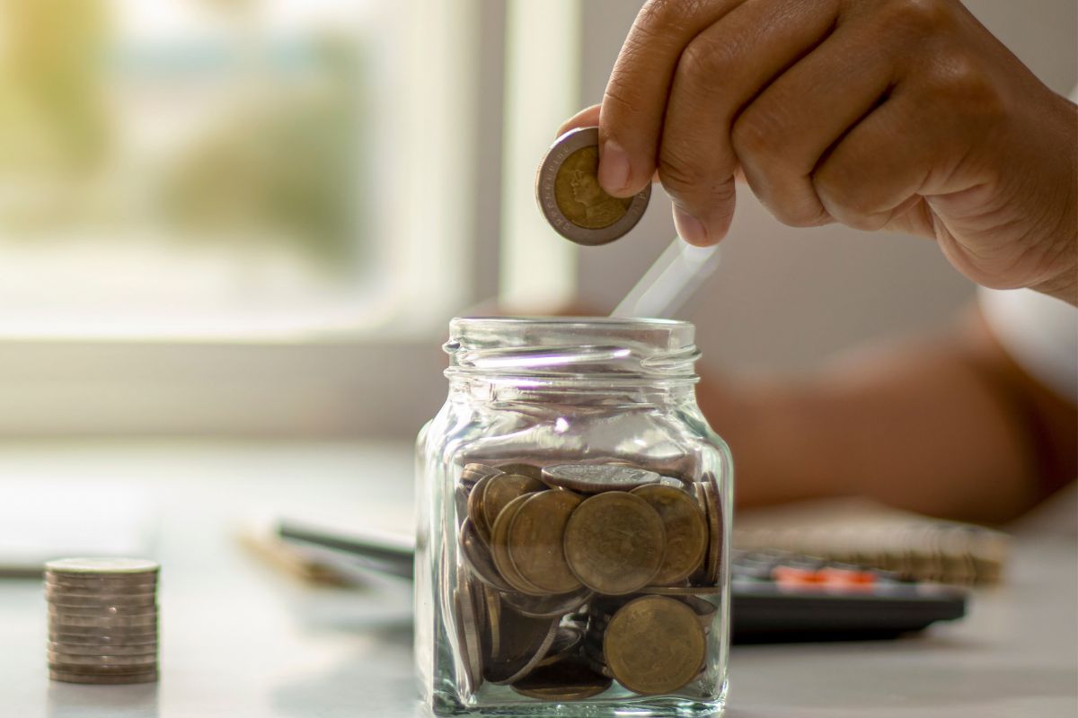 A picture of someone putting a coin in the jar. 