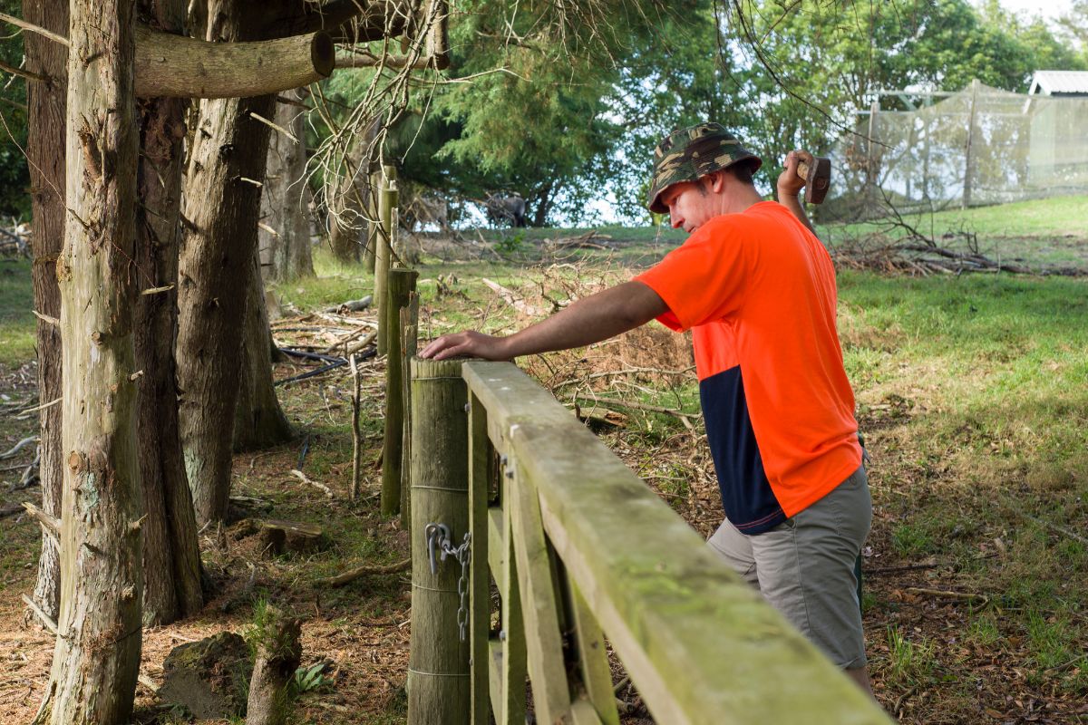 A picture of someone fixing a fence. 