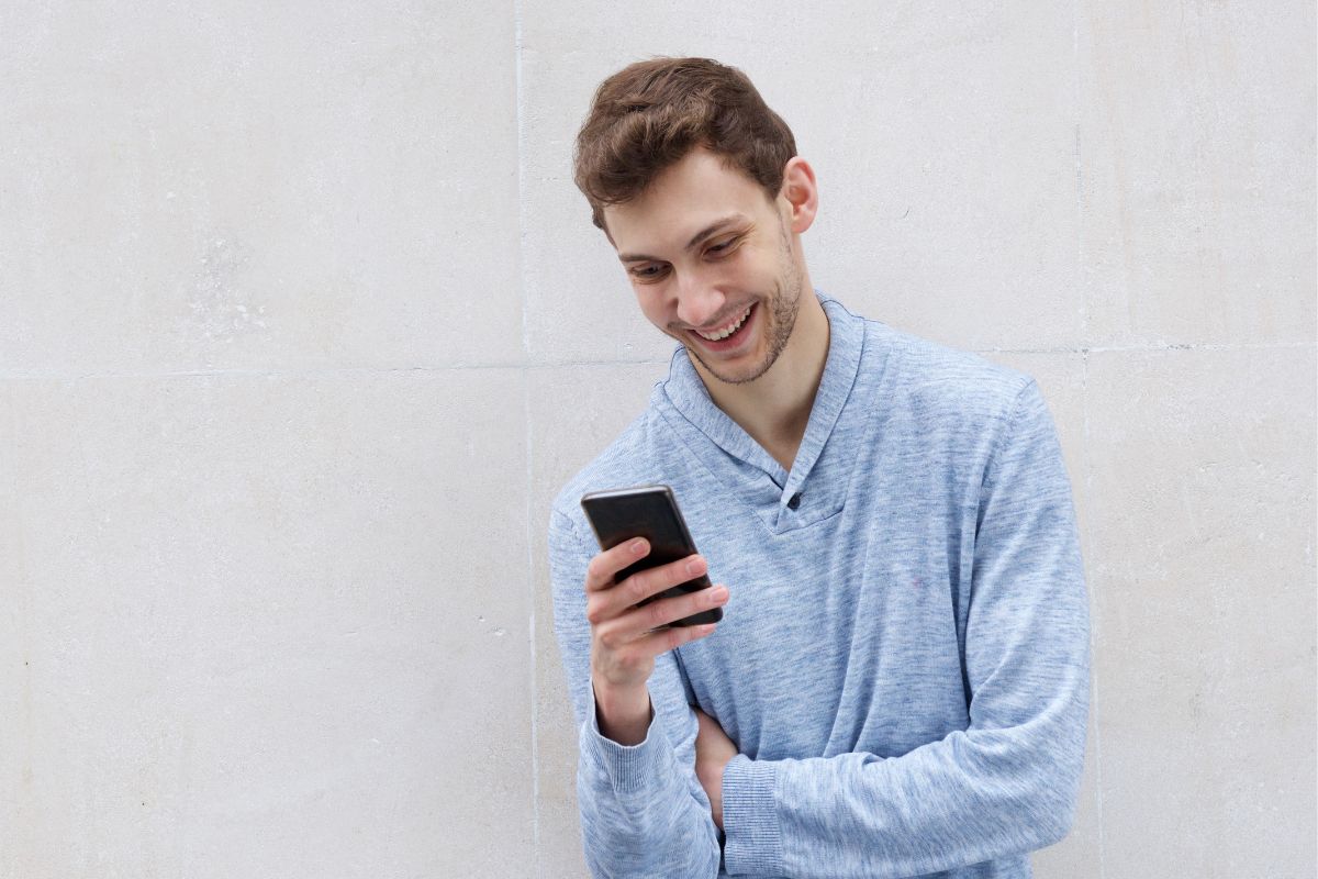 A picture of someone smiling while using their phone.