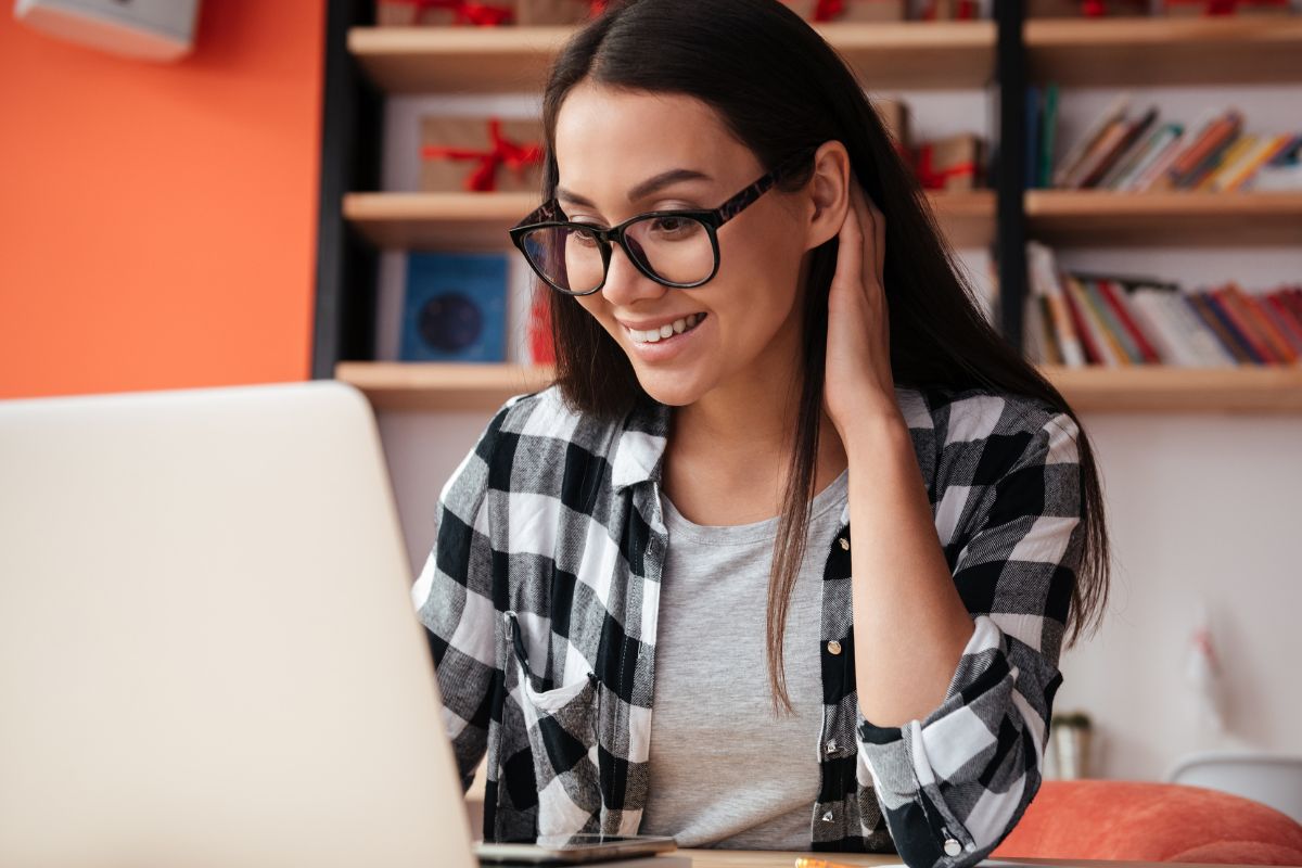 A picture of someone smiling while using their laptop.