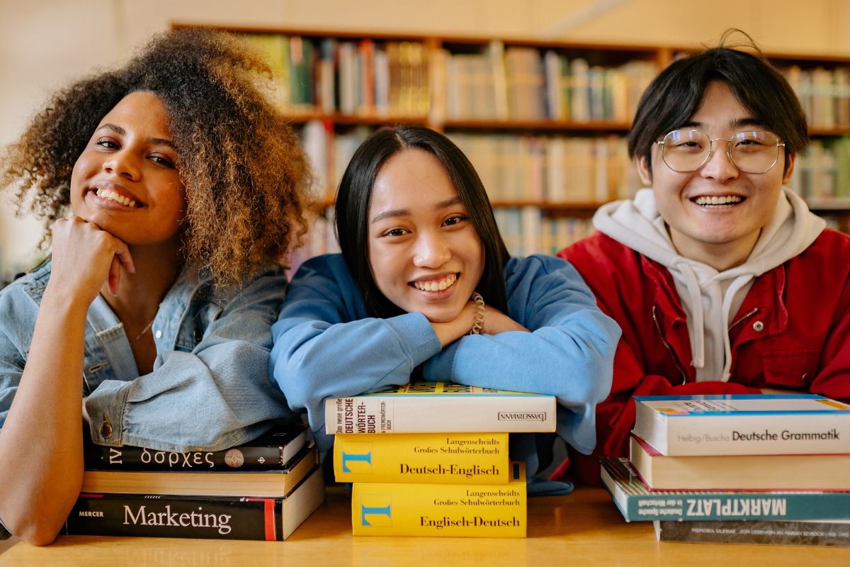 A picture of teens smiling on a library.