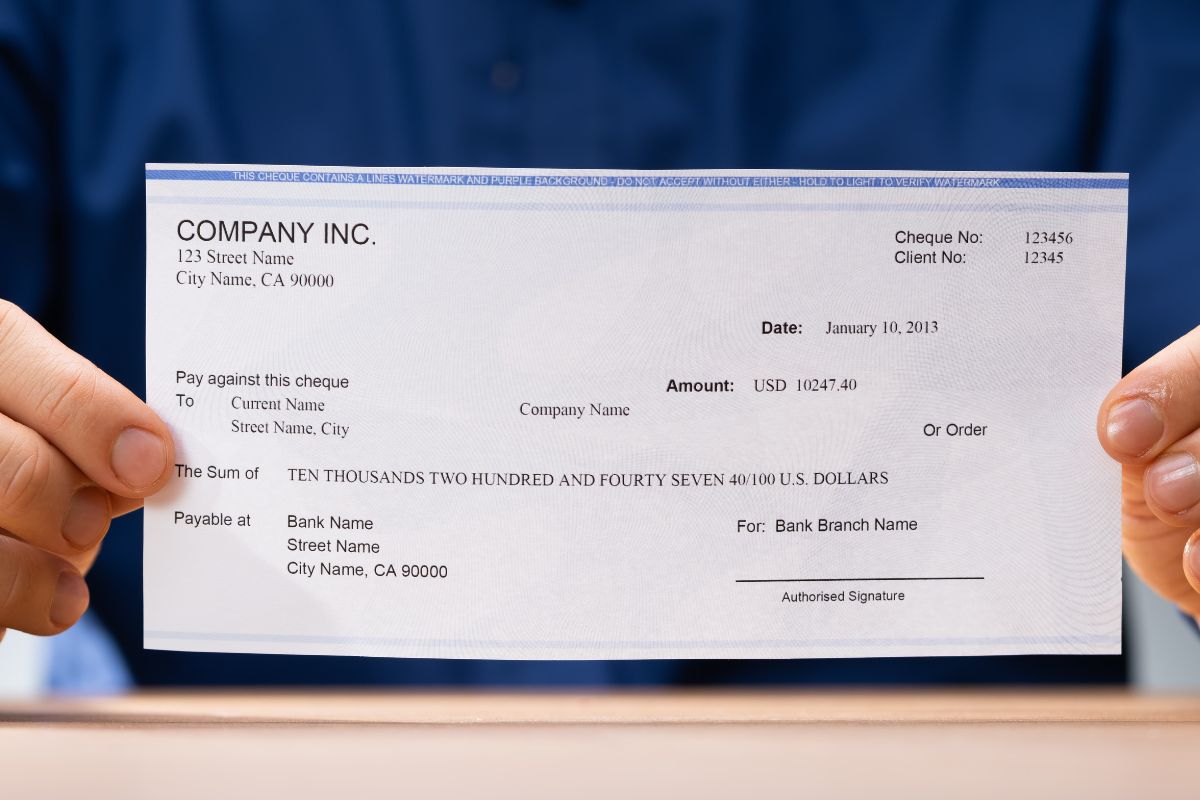 Image of a man's hand holding a paycheck.