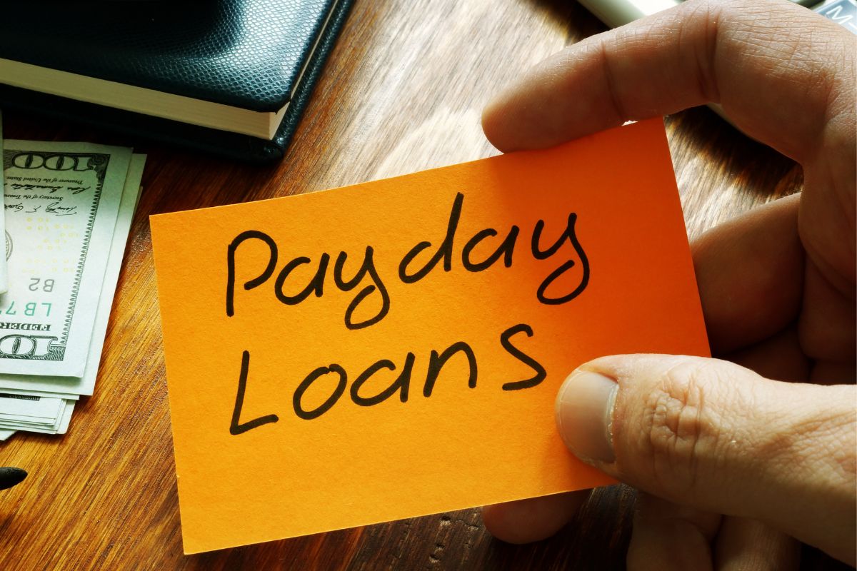 Image of a man's hand holding a paper with the payday loans wording.