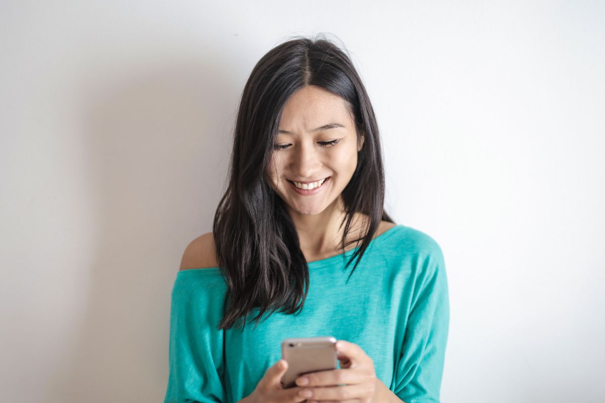 A picture of someone smiling while using their phone.