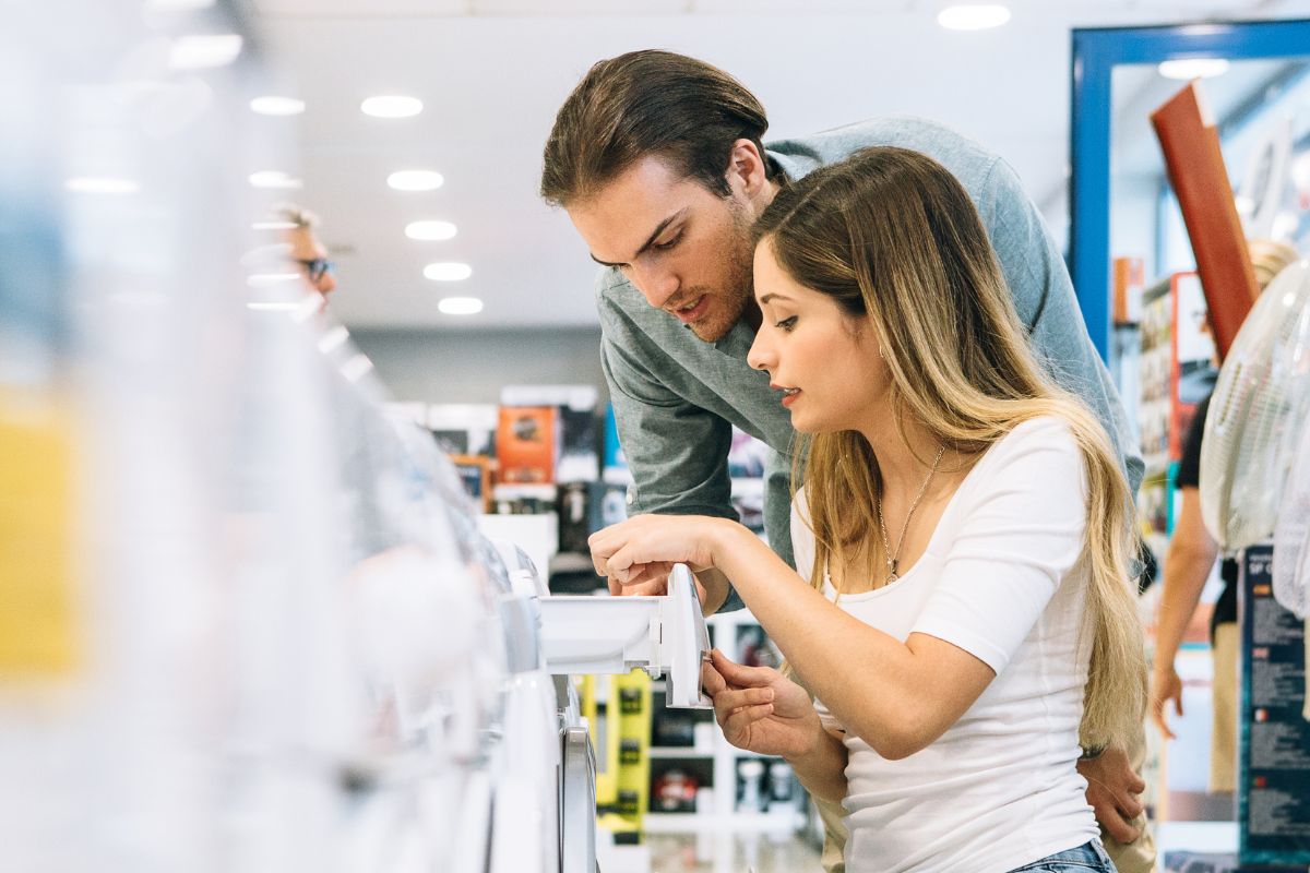 A picture of a couple picking a appliance to buy.