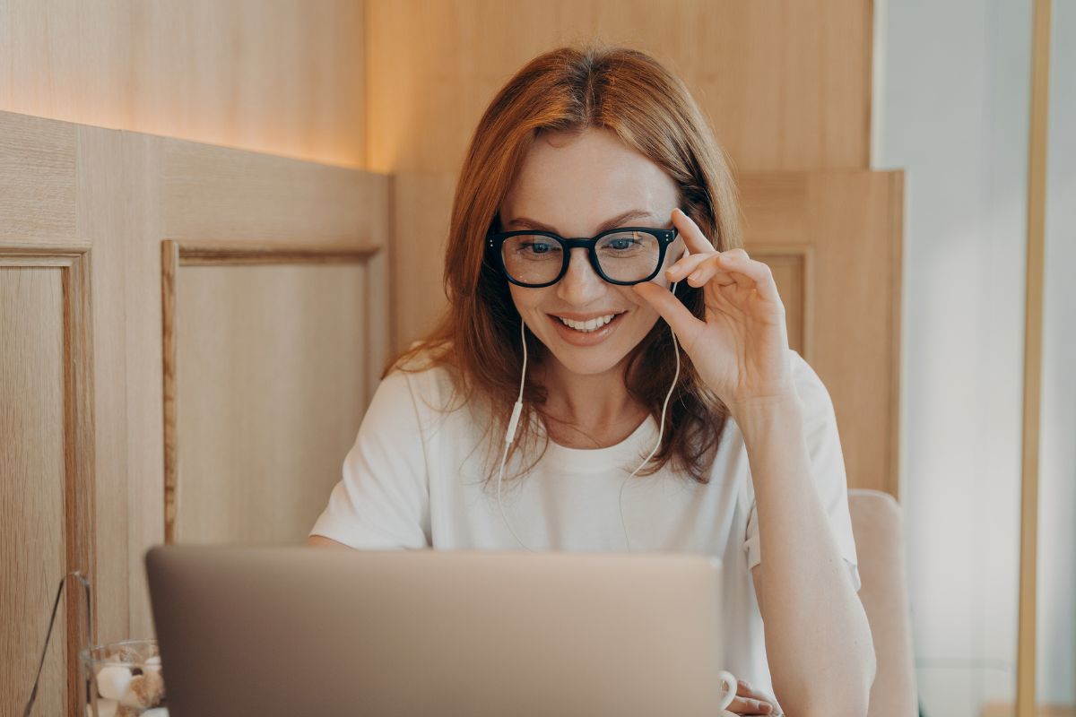 A foto de uma mulher sorrindo enquanto usa seu laptop. 