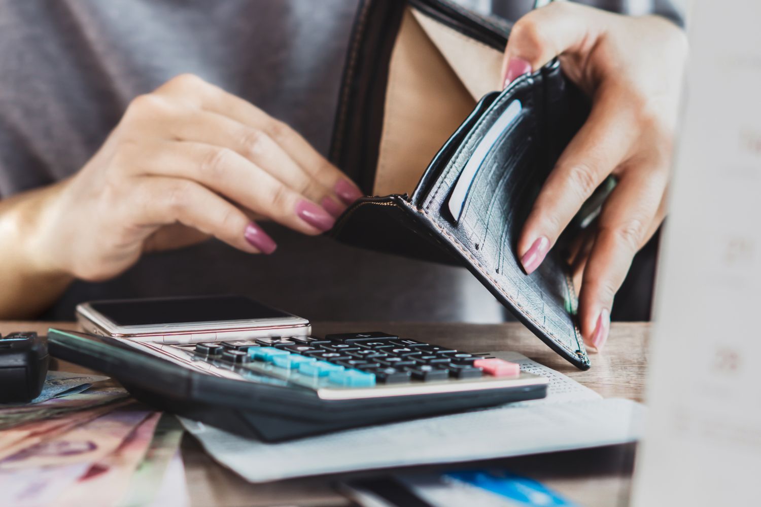 A picture of someone reaching to their empty wallet.