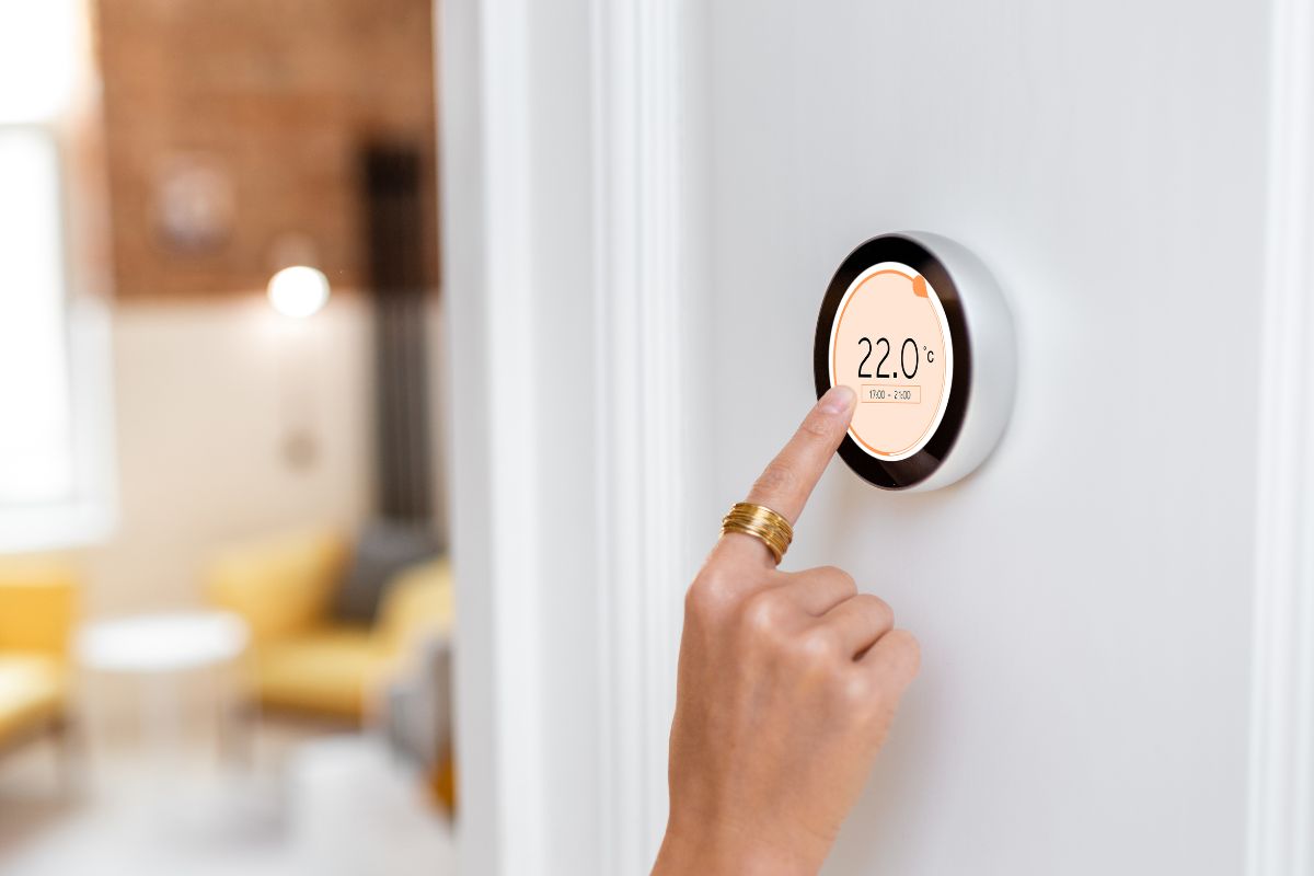 A picture of someone turning the thermostat up.