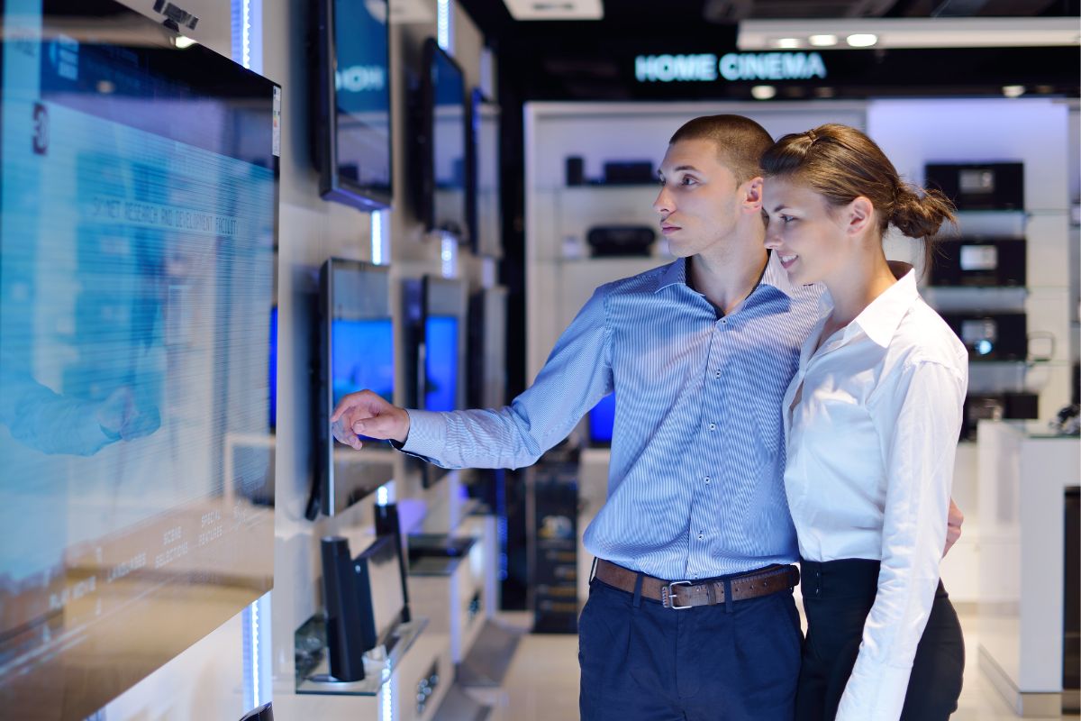 A picture of a couple buying a TV.