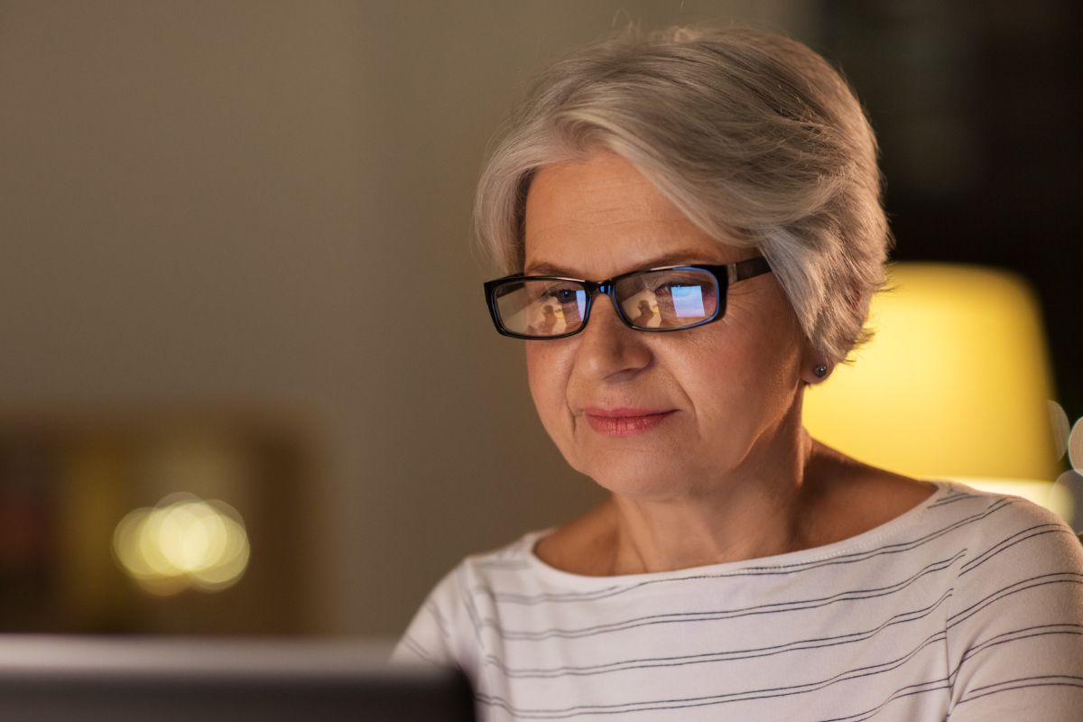 A picture of an elderly woman researching something.