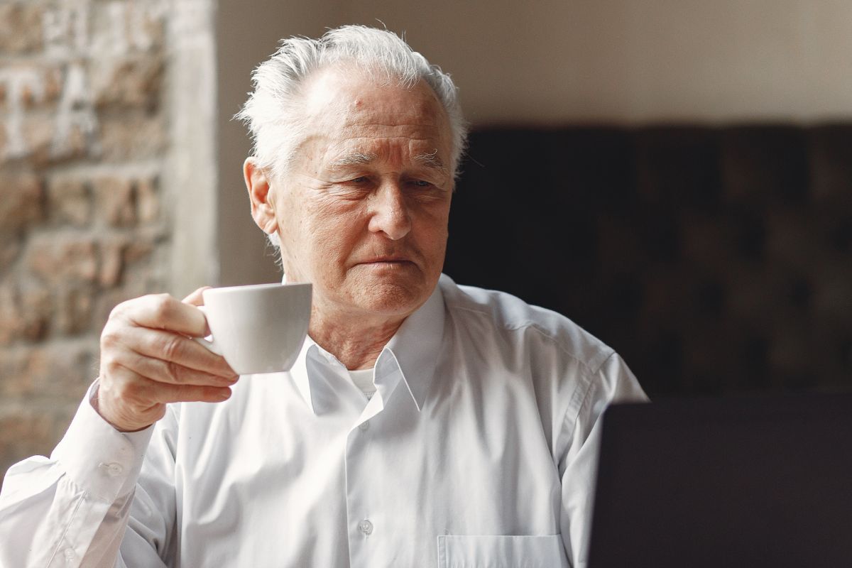 A picture of an elderly man sipping something.
