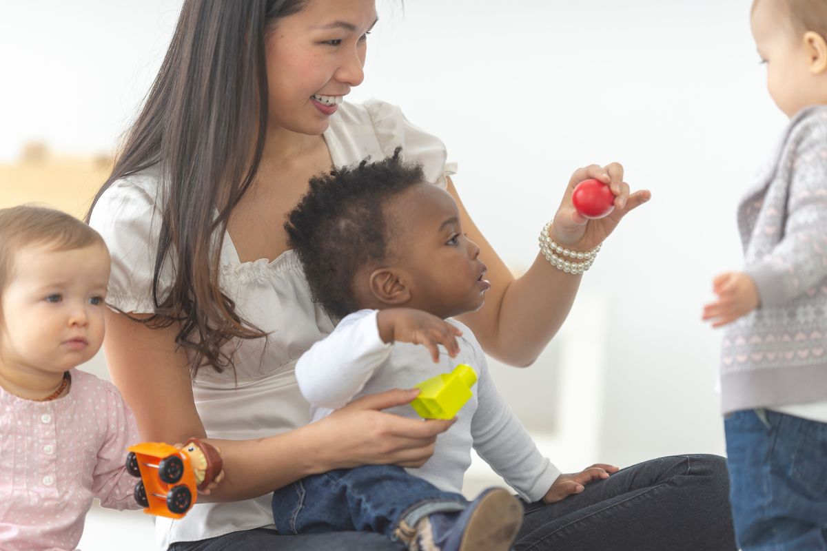 A picture of a babysitter playing with kids.