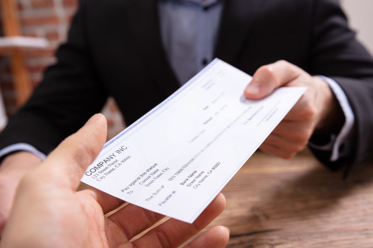 An image of a man's hand receiving his paycheck.