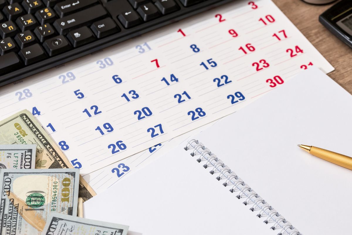 A picture shows money, a calendar, a notebook, and a pen.