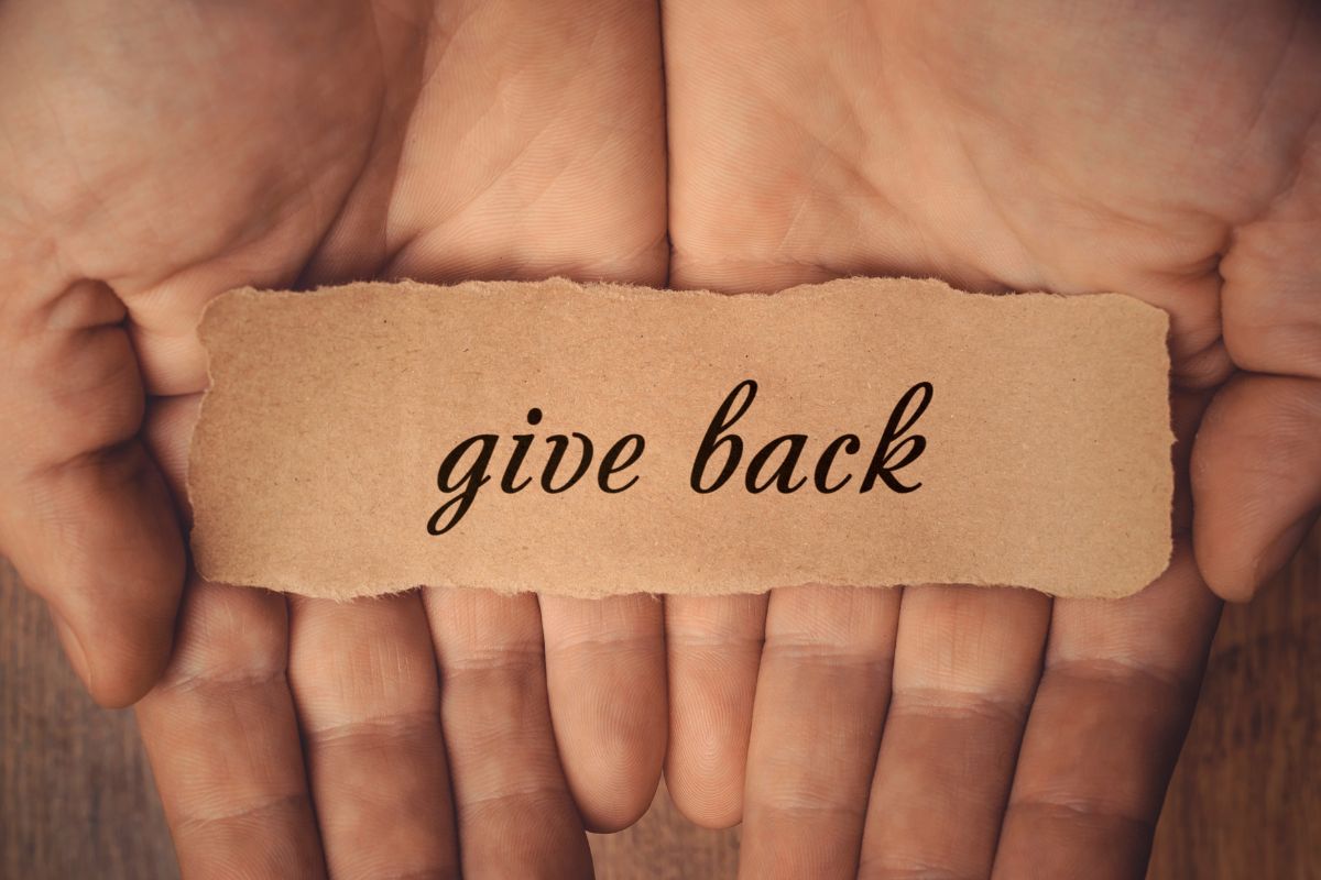 A picture of a lady's hand and a paper with a give-back wording.