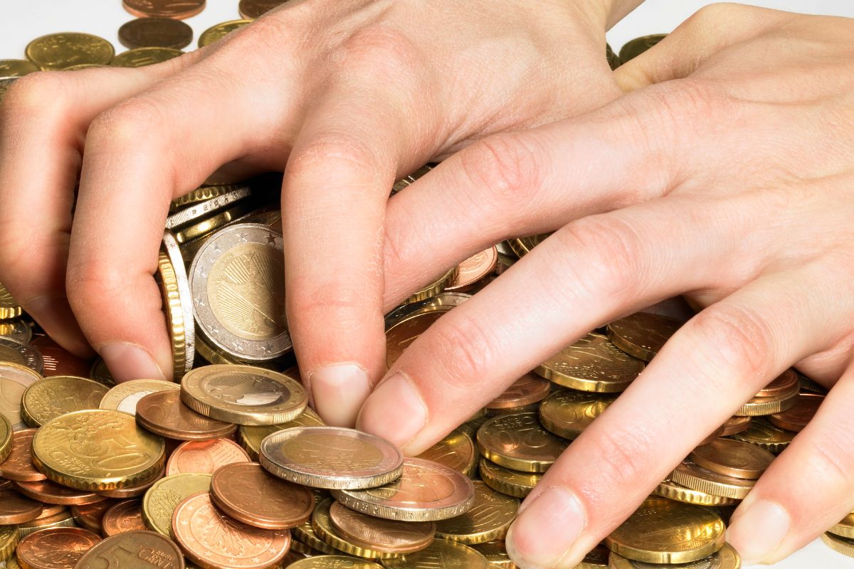 A picture shows a man's hand gathering coins.