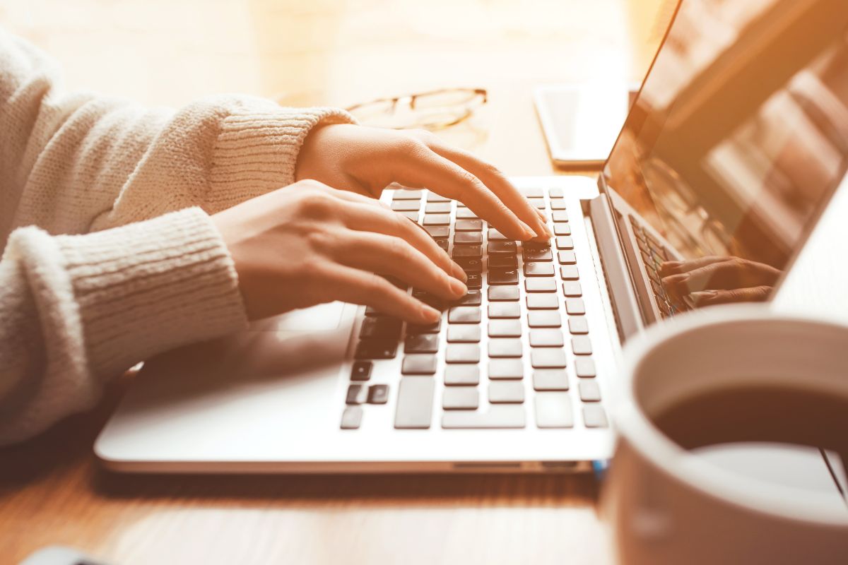 A picture of a woman's hand typing on a laptop.