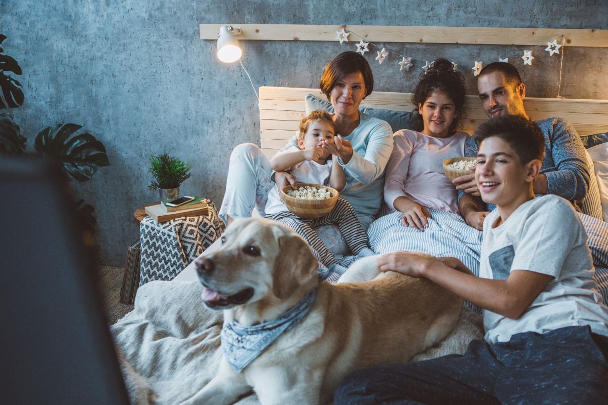 A picture of a family at the bed having a movie together.