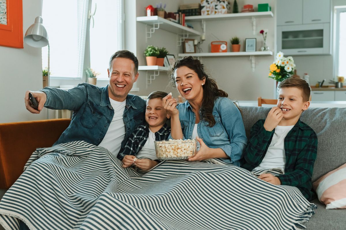 A picture of a family laughing while watching a movie.