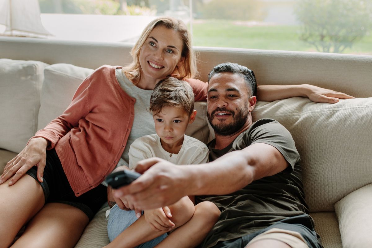 The picture shows parents and their kid watching a movie.
