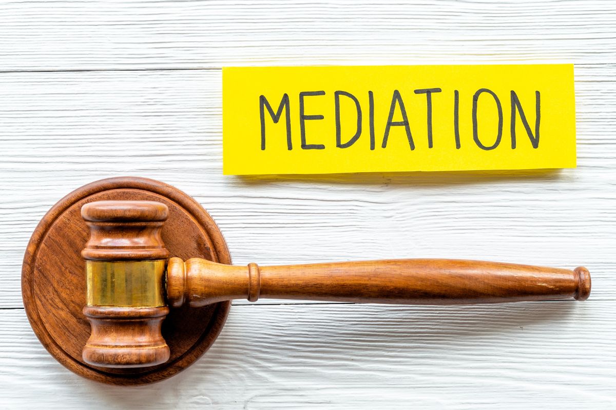 A picture of a judge's gavel and a paper with mediation wording.