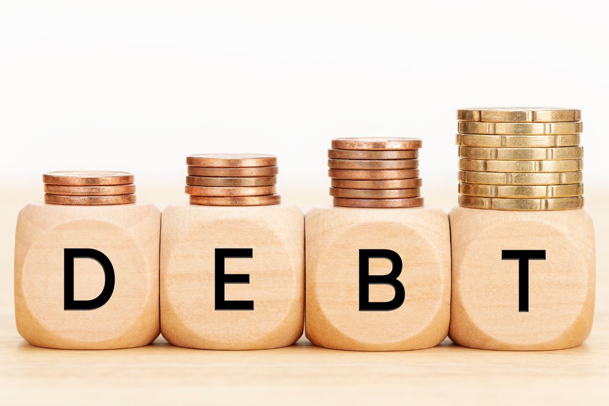 A picture shows a debt word and coins.