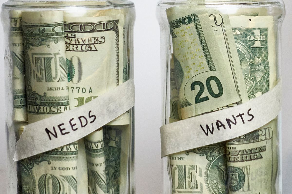 A picture shows jars with money for wants and needs.