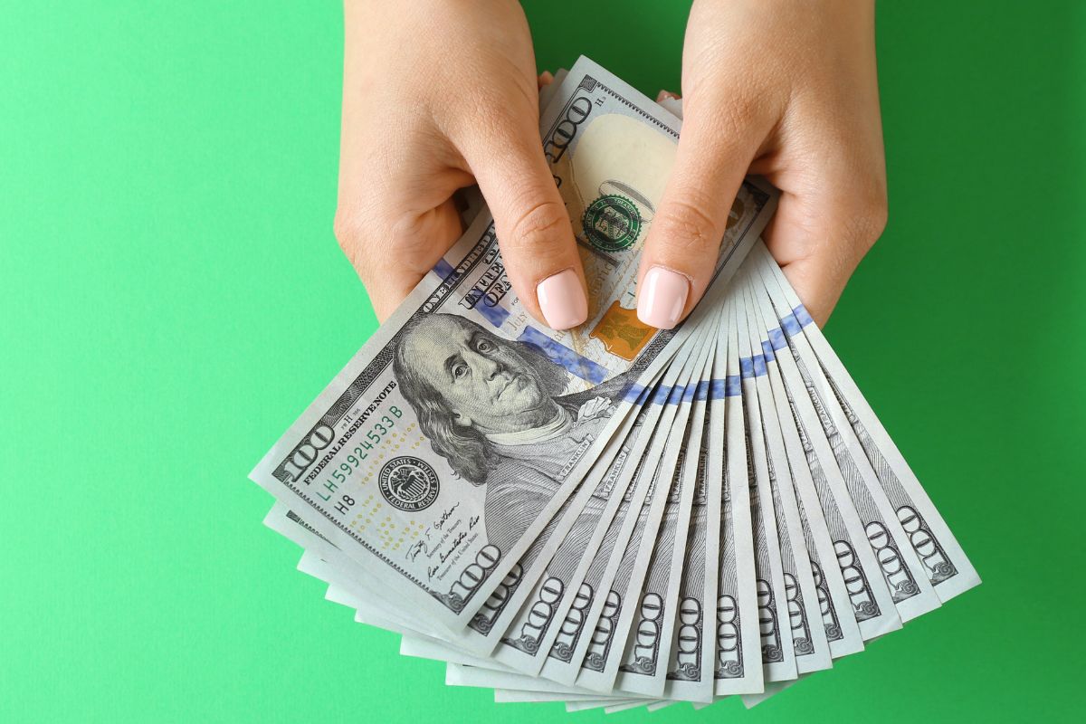 An image shows a woman's hand holding money.
