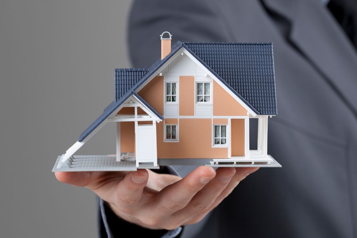 A picture shows a man's hand holding a mini house.